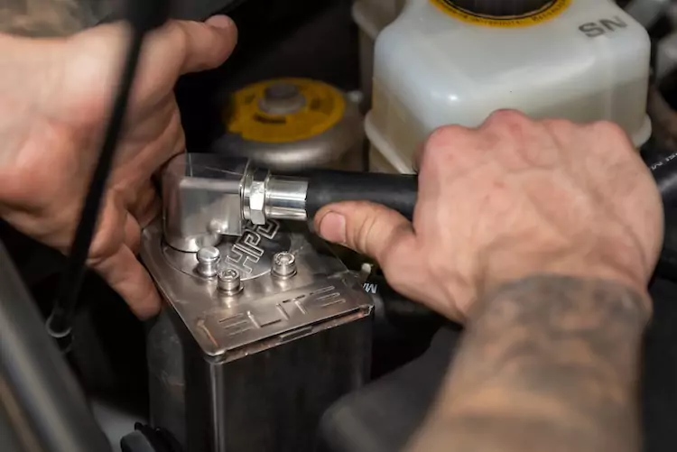 Mechanic using a tool to install a catch can